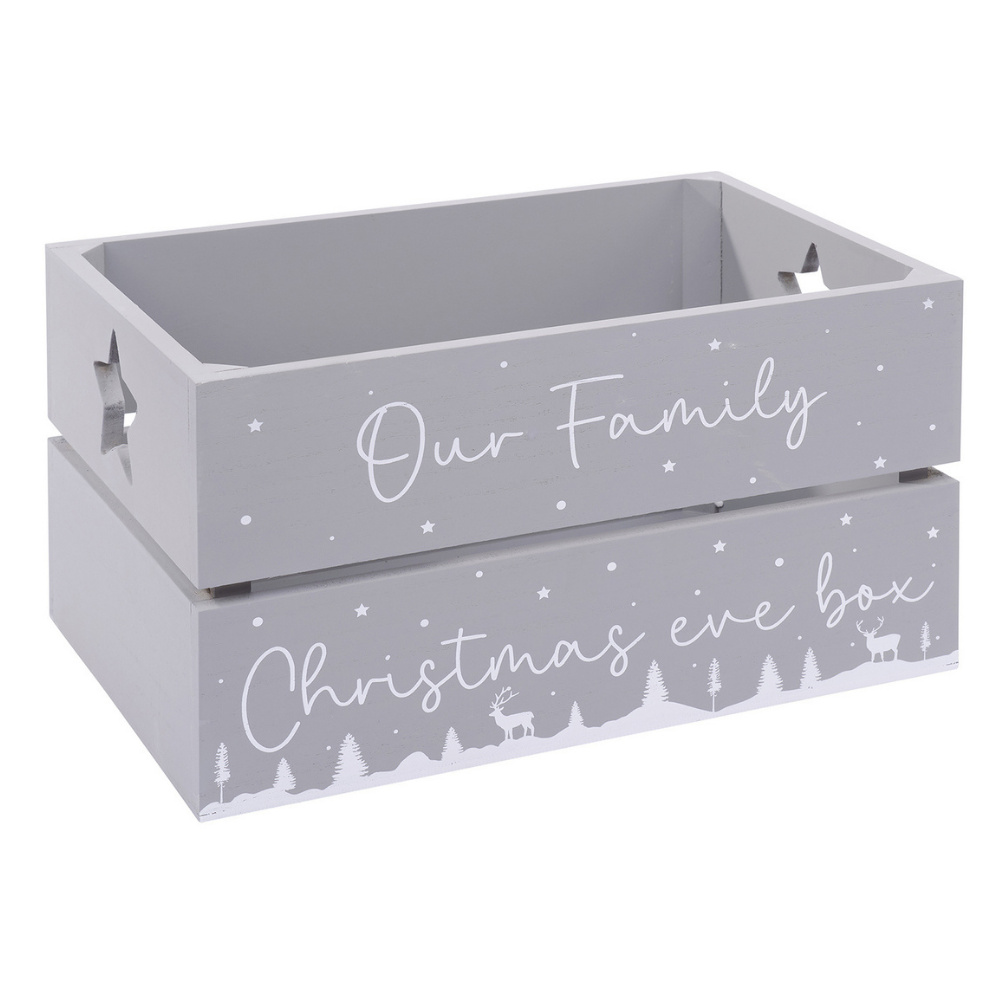 grey wooden christmas eve wooden crate box.  Feature the words Our Family Christmas Eve Box on the front and has a snowy scene design painted below with trees and deer.  There are 2 star cut-outs on each side of the box