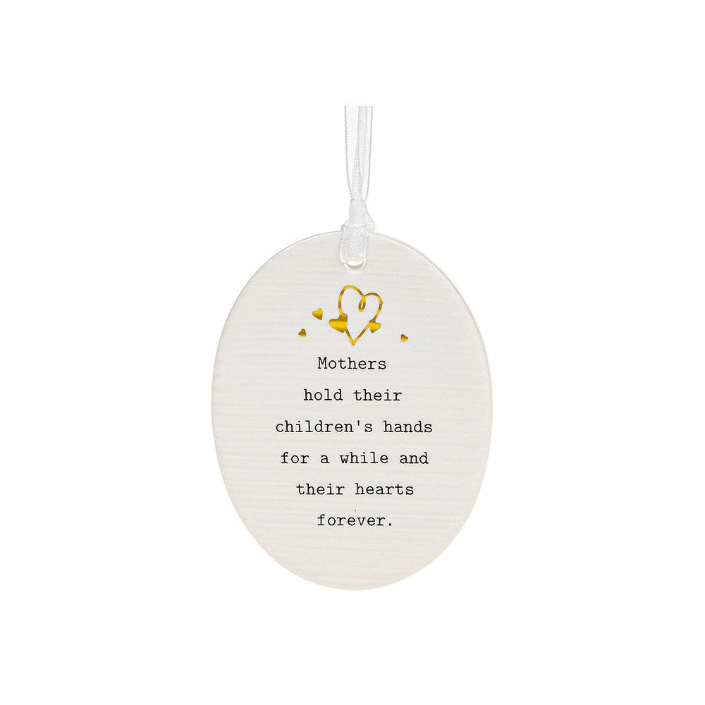 White oval shaped porcelain plaque with white organza ribbon with the words mothers hold their children's hands for a while and their hearts forever in black text.  There are little gold hearts decorated the top of the hanger above the writing