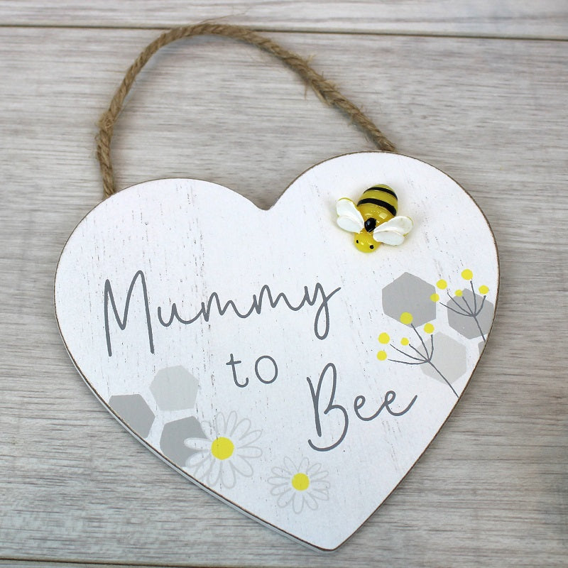 wooden heart shaped hanging plaque with the words mummy to be in grey script writing and a little three dimensional yellow bee on the corner.