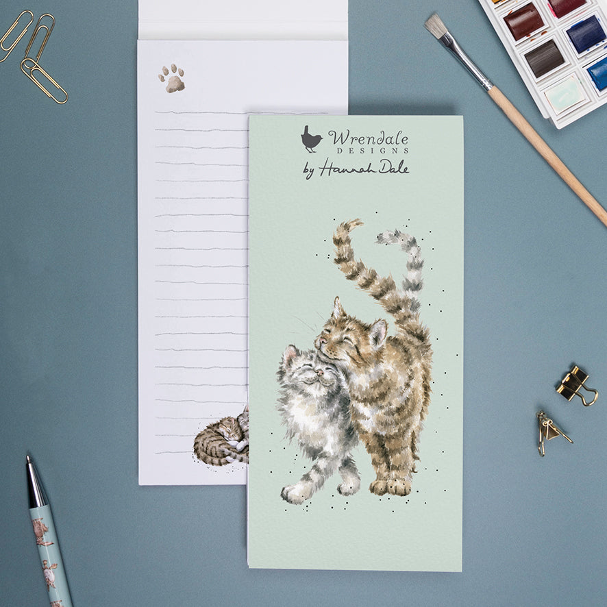 shopping list notebook with a pale green cover and illustration of 2 cats cuddling together.