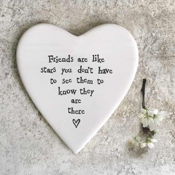 a white heart shape porcelain coaster with the words, Friends are like stars you don't have to see them to know they are there printed on in black text.  