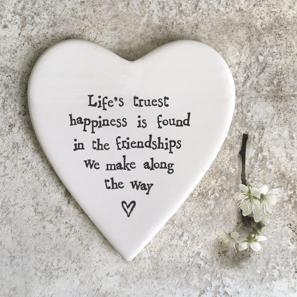 white porcelain heart shape drinks coaster  with the words Life's truest happiness is found in the friendships we make along the way printed on the front in black text 