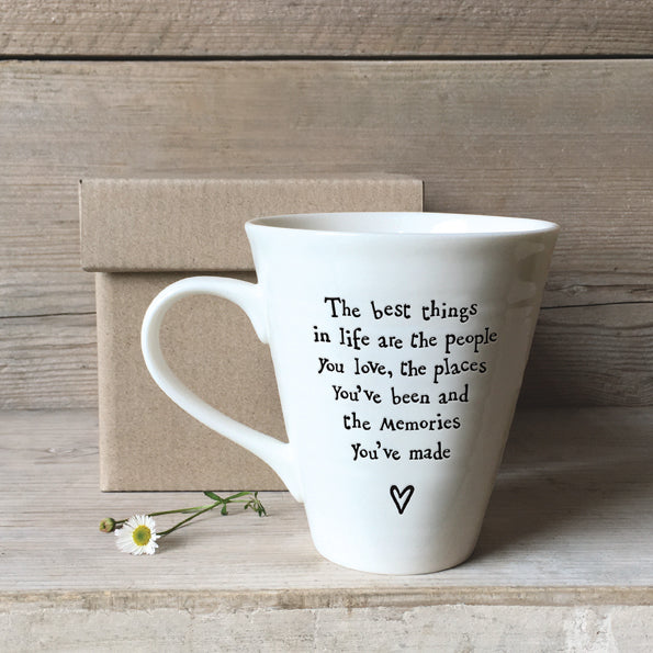 white porcelain conical shape mug with the words the best things in life are the people you love the places you've been and the memories you've made in black jaunty style text.  There is a little heart symbol below the text. The mug is pictured in front of a box.