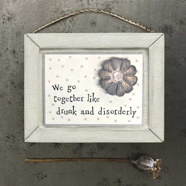 wooden hanging sign with the words we go together like drunk and disorderly in jaunty style writing. There is a little grey wooden flower on the front of the sign.