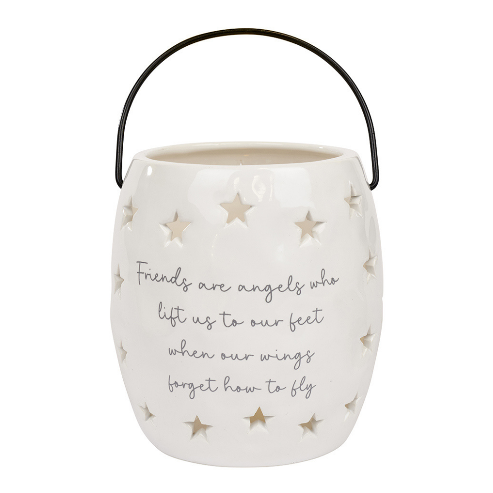 white ceramic lantern candle holder with star cut outs.  front of the lantern features the words, friends are angels who lift us to our feet when our wings forget to fly