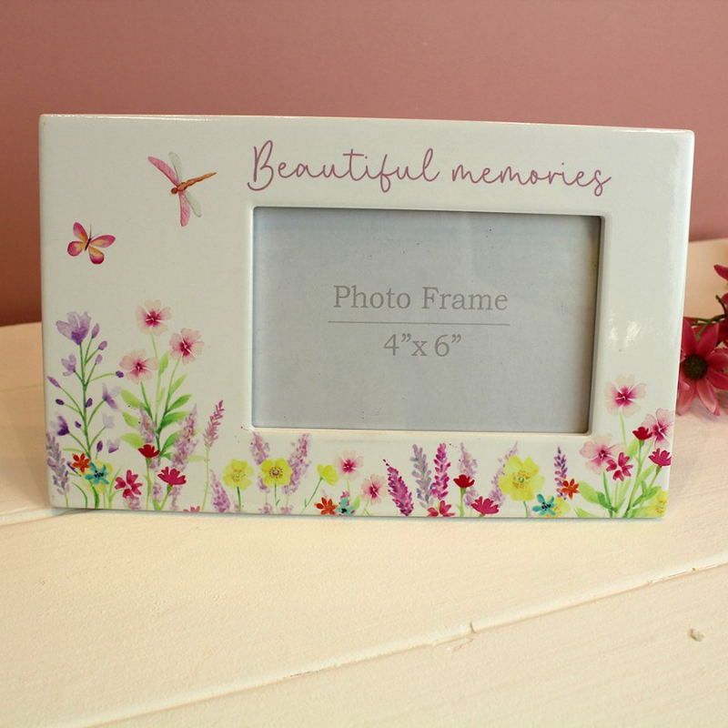 white ceramic photo frame with colourful floral meadow design on the front and the words beautiful memories on the top.  The photo frame also features a butterfly and a dragonfly.  Suitable for a 4 x 6" landscape style photo